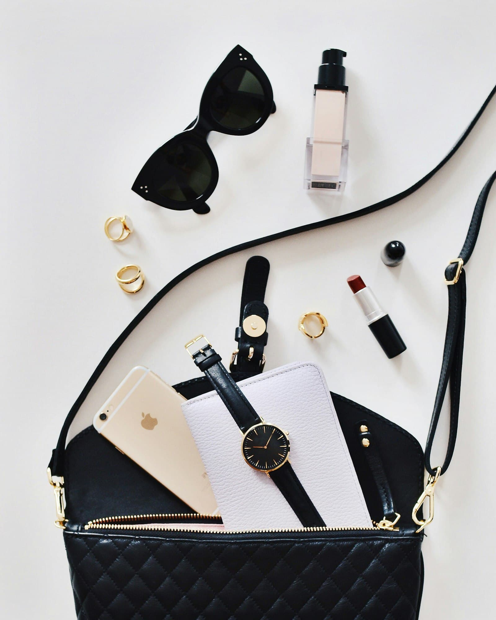 Accessories flat lay with a quilted bag, watch, and sunglasses