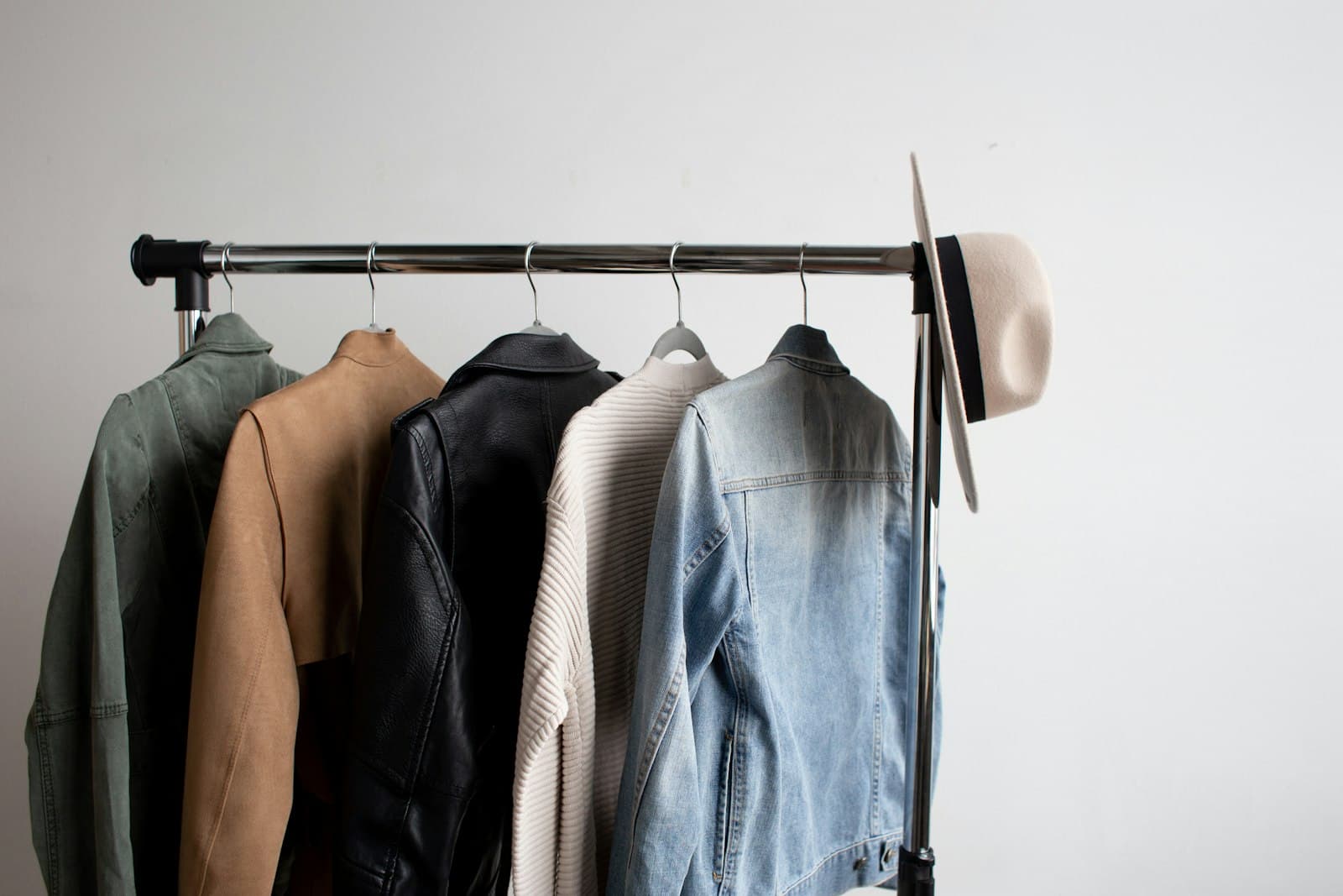 Jackets and a cream felt hat on a garment rack