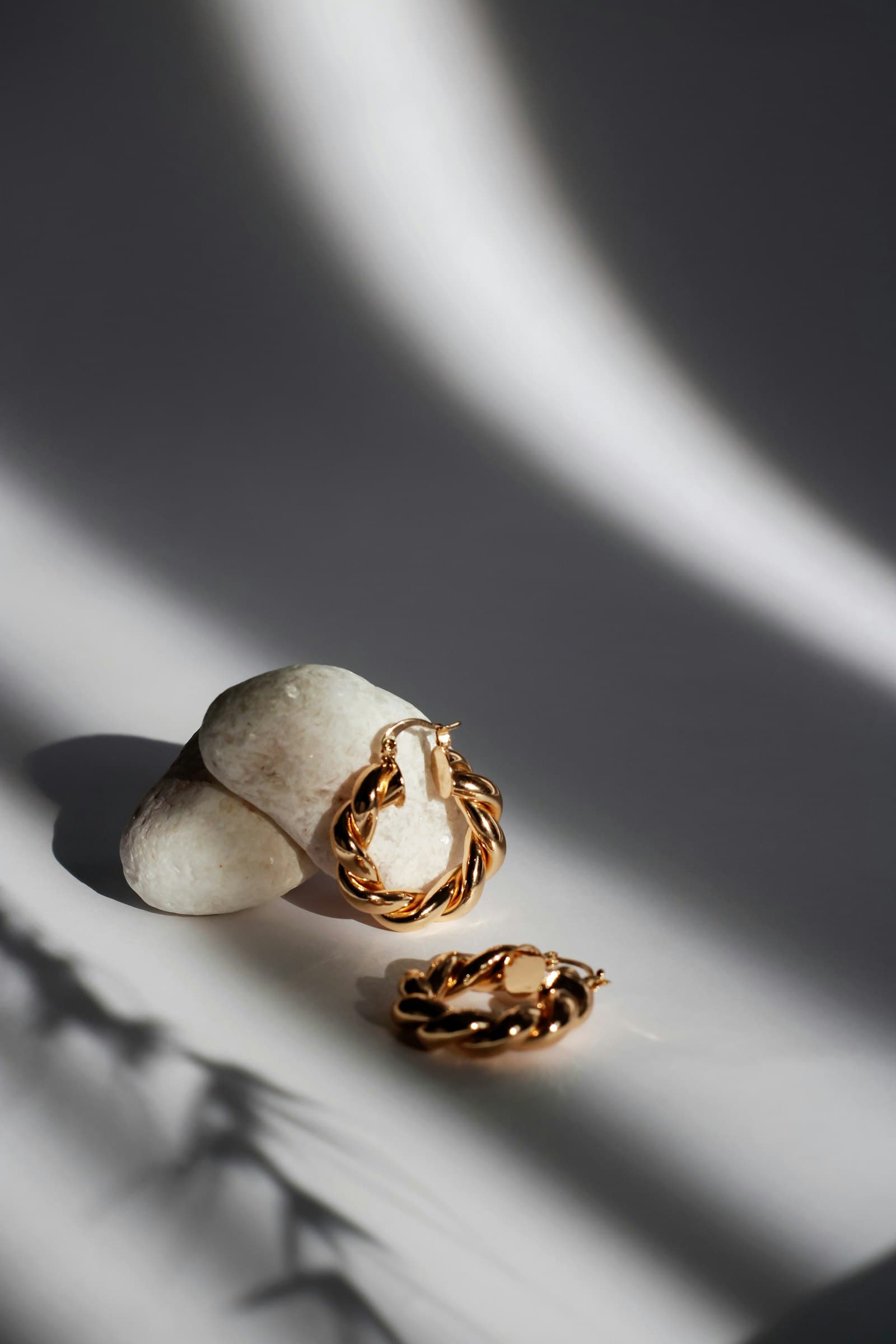 Handmade gold twisted hoop earrings displayed in dramatic light