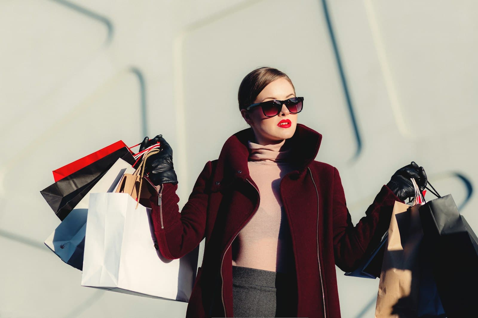 Stylish woman in sunglasses carrying colorful shopping bags
