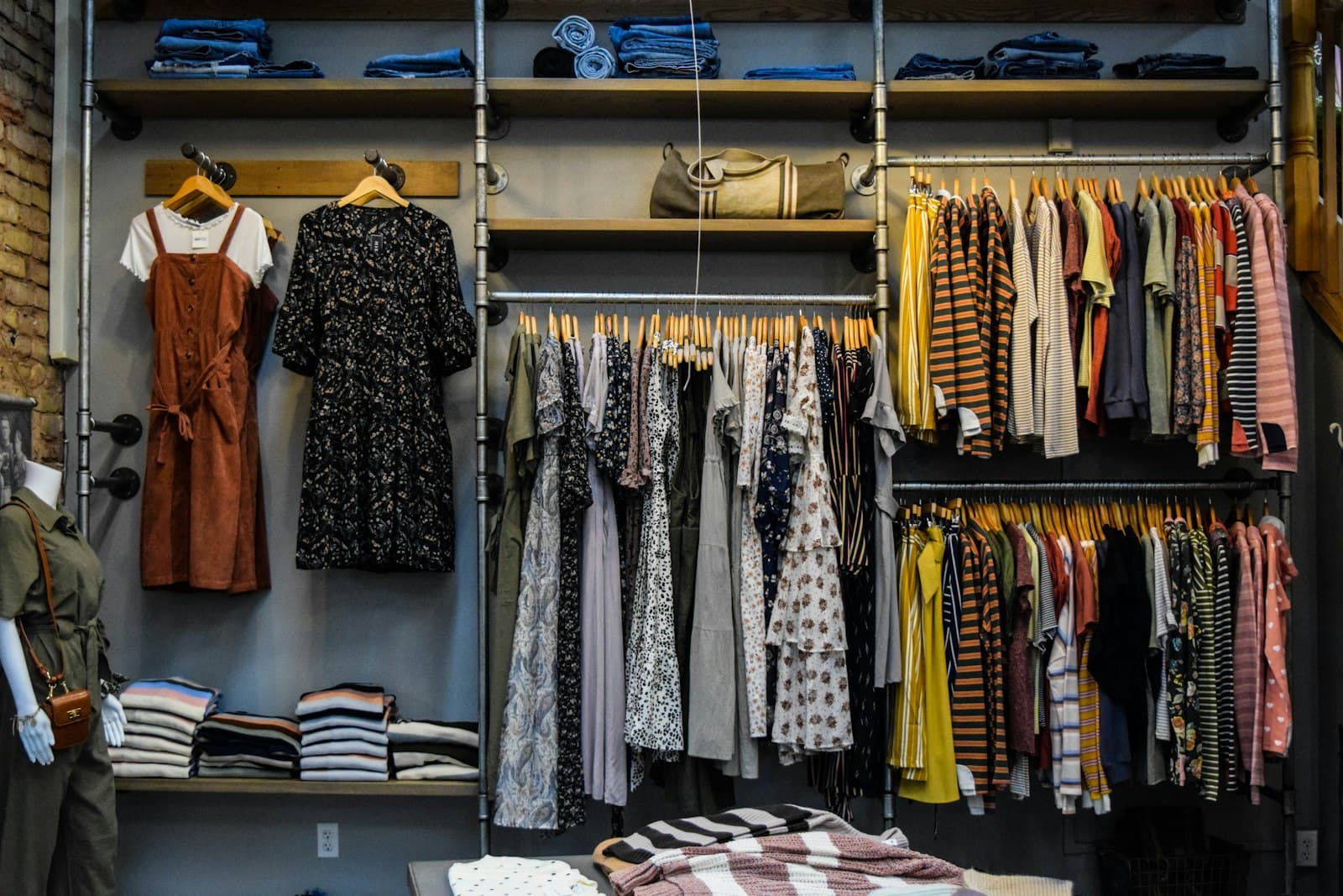 Boutique interior with racks of dresses, folded knits, and a styled mannequin