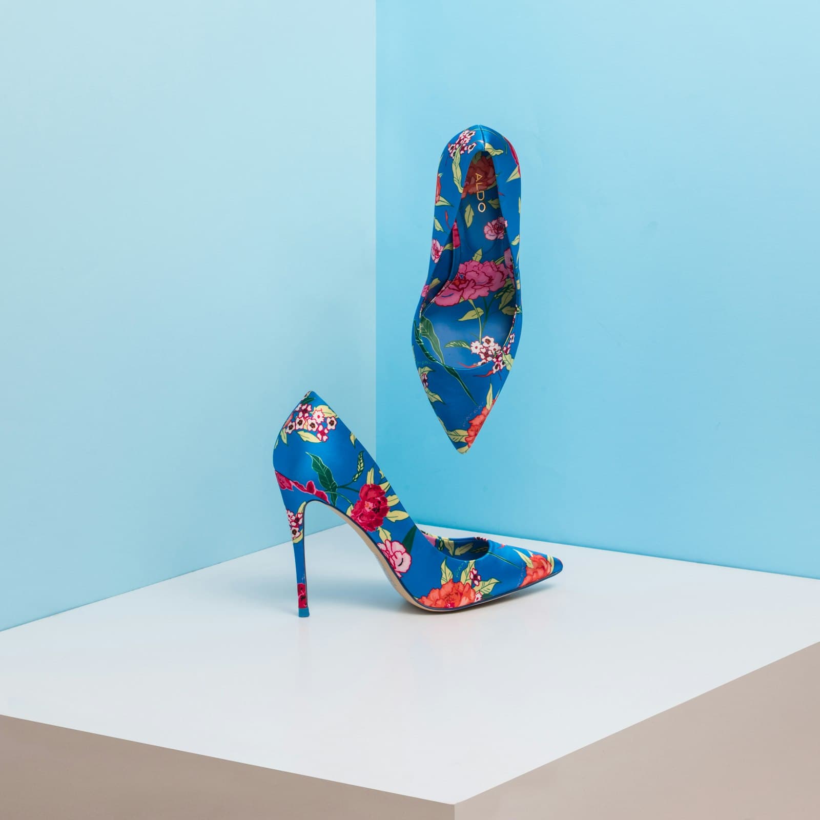 Blue satin pointed-toe pumps with a pink and red floral print