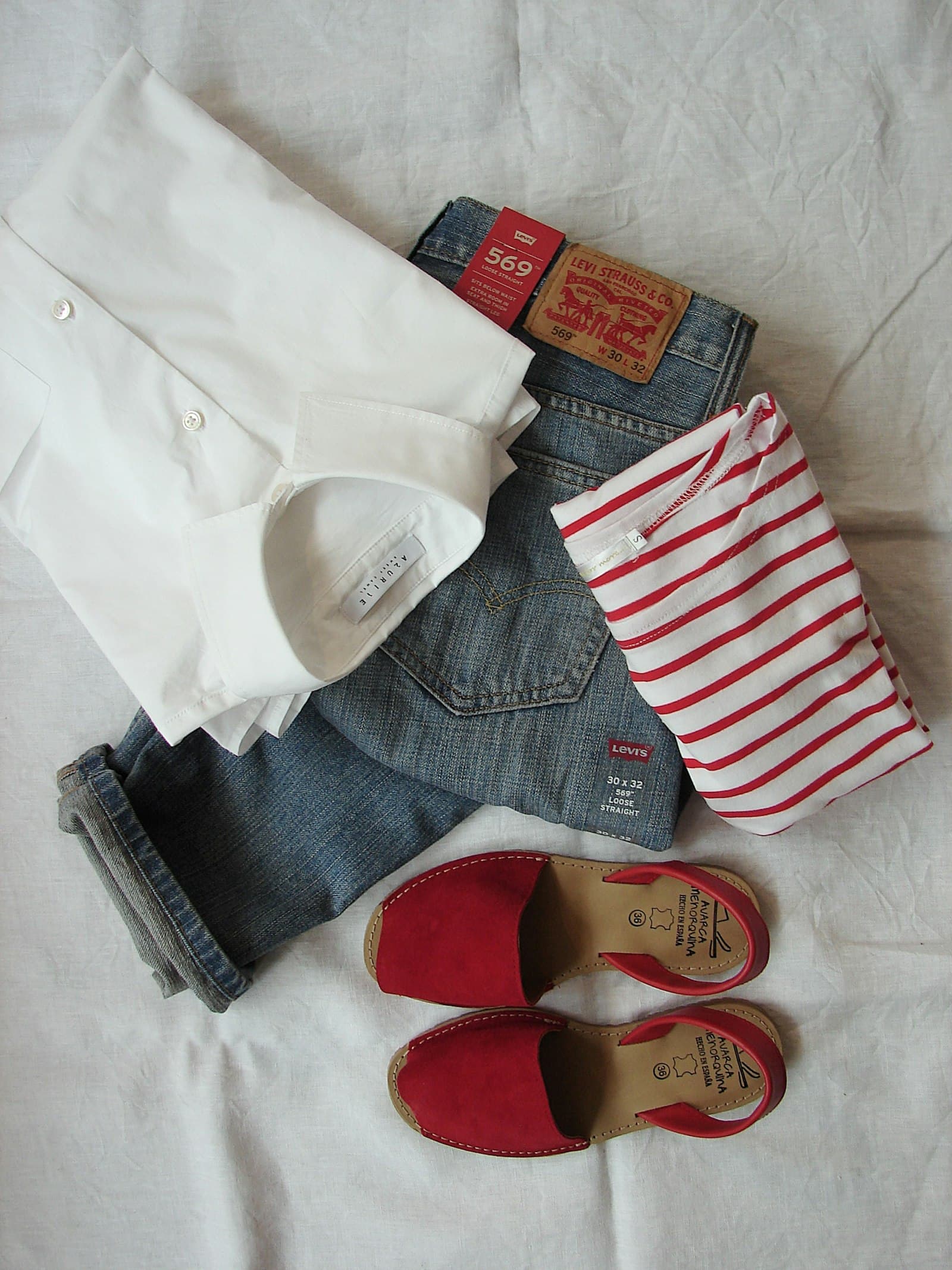 Outfit flat lay with a red striped tee, jeans, and red sandals